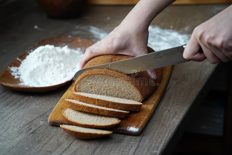 Eine Frau Schneidet Ein Brotlaib Auf Den Tisch Stockbild - Bild von