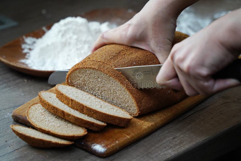 Eine Frau Schneidet Ein Brotlaib Auf Den Tisch Stockbild - Bild von