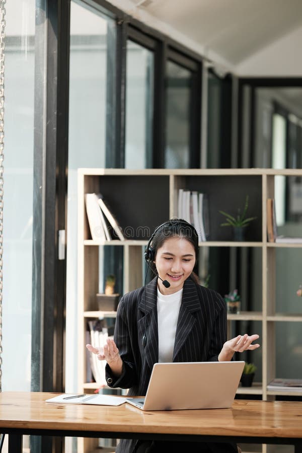 Eine Frau sitzt an einem Schreibtisch mit einem Laptop und einem Headset auf lizenzfreies stockfoto