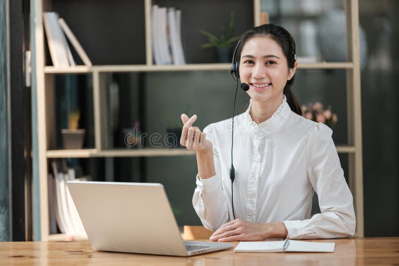 Eine Frau sitzt an einem Schreibtisch mit einem Laptop und einem Headset auf lizenzfreie stockbilder