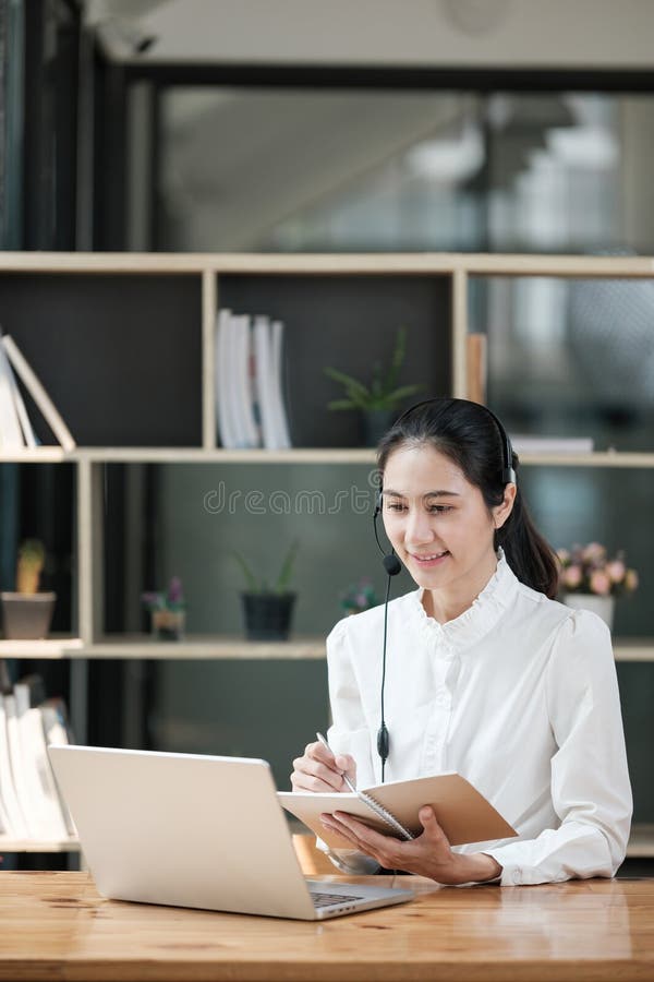 Eine Frau sitzt an einem Schreibtisch mit Laptop und Notebook. sie lächelt und genießt ihre Arbeit