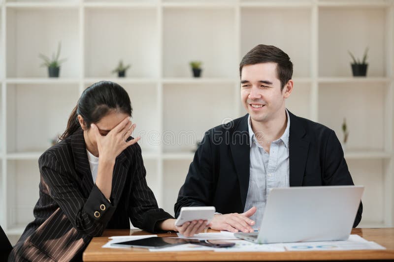 Eine Frau sitzt an einem Schreibtisch mit einem Mann neben ihr stockfotos