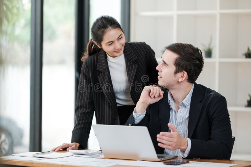 Eine Frau und ein Mann sitzen an einem Schreibtisch mit einem Laptop vor ihnen lizenzfreies stockfoto
