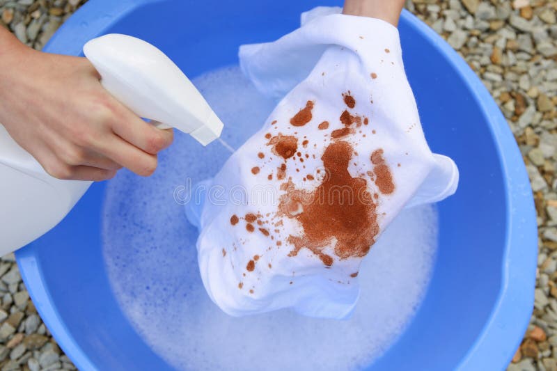 A woman is trying to wash off a stain on white clothes. A woman is trying to wash off a stain on white clothes.