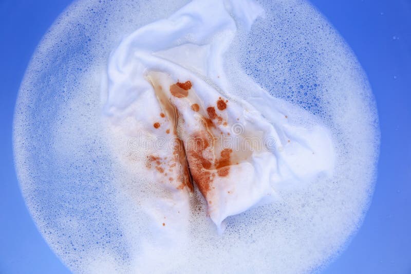 A woman is trying to wash off a stain on white clothes. A woman is trying to wash off a stain on white clothes.