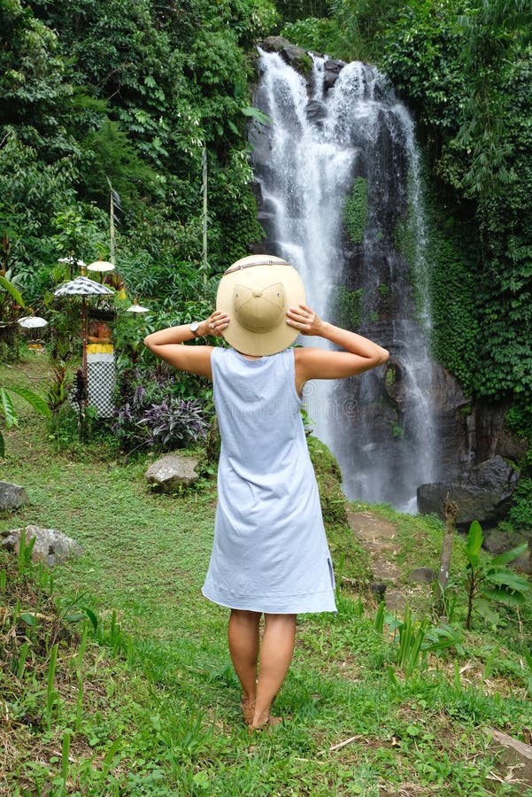 Eine Frauenstellung und Bewundern des wilden Wasserfall- und Dschungelwaldes, Bali stockfotografie Eine Frauenstellung und Bewundern des wilden Wasserfall- und Dschungelwaldes, Bali stockfotografie