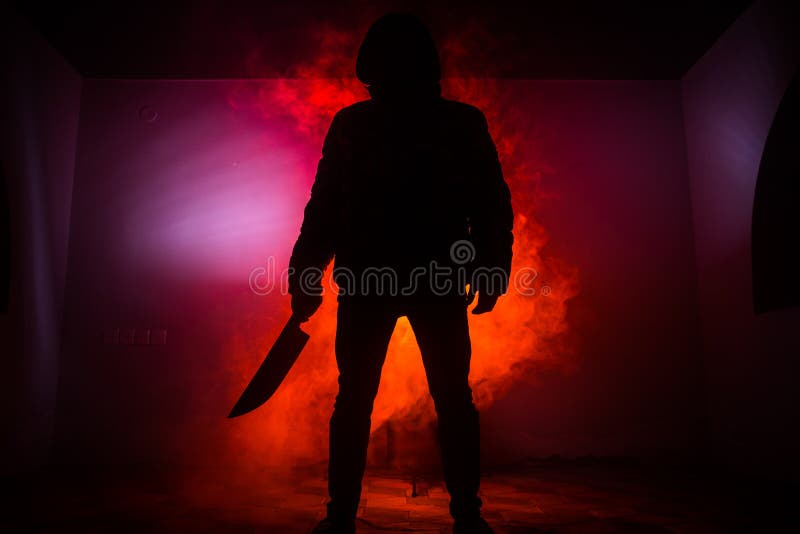Eine gefährliche mit Kapuze Mannstellung in der Dunkelheit und Halten eines Messers Gesicht kann nicht gesehen werden Begehen ein