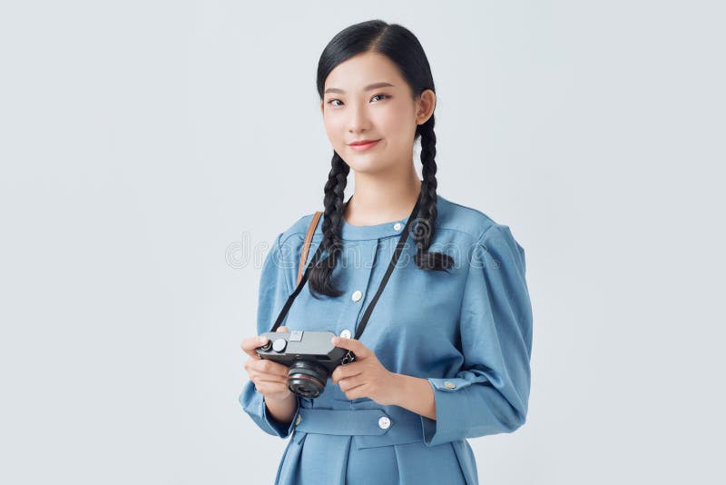 Eine glückliche und lächelnde junge Frau, die eine Digitalkamera verwendet, die auf weißem Hintergrund isoliert ist stockbild