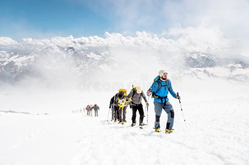 Eine Gruppe Bergsteiger klettert zur Spitze eines Schnee-mit einer Kappe bedeckten Berges stockbild Eine Gruppe Bergsteiger klettert zur Spitze eines Schnee-mit einer Kappe bedeckten Berges stockbild