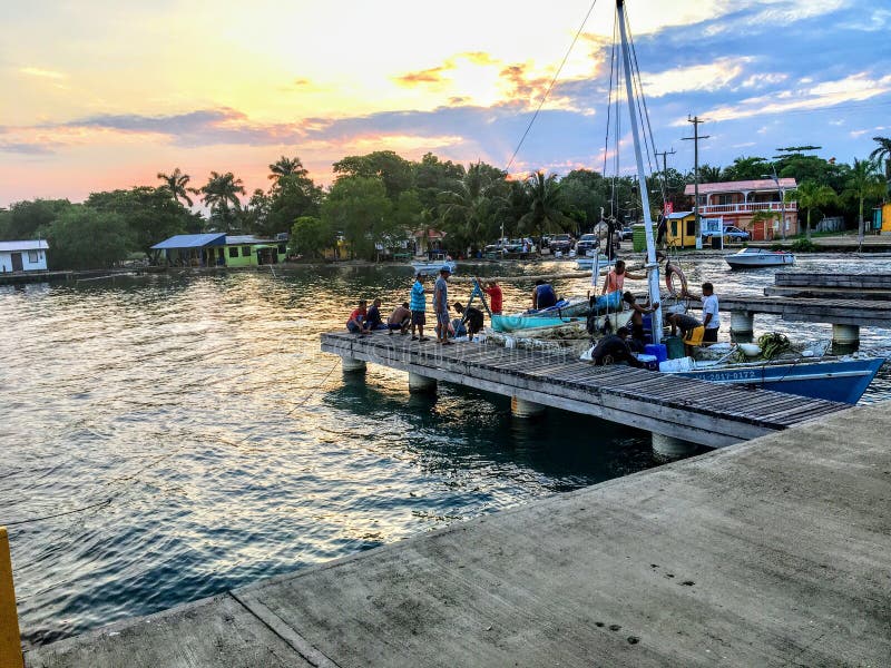 Eine Gruppe des lokalen belizischen Fischers ihr Boot zum Dock nach einem Tag des Fischens als die Sonnens?tze zur?ckbringen lizenzfreies stockfoto Eine Gruppe des lokalen belizischen Fischers ihr Boot zum Dock nach einem Tag des Fischens als die Sonnens?tze zur?ckbringen lizenzfreies stockfoto