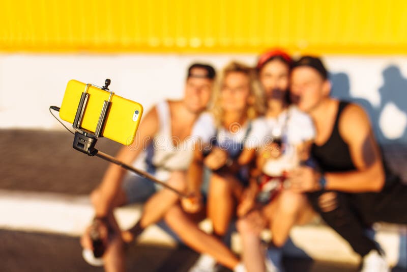Eine Gruppe Freunde macht ein selfie, das auf der Pflasterung, die Firma von den jungen Leuten sitzt, die Fotos mit einem selfie stockfotografie Eine Gruppe Freunde macht ein selfie, das auf der Pflasterung, die Firma von den jungen Leuten sitzt, die Fotos mit einem selfie stockfotografie