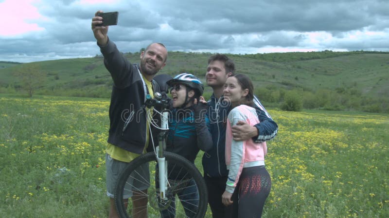 Eine Gruppe glückliche Touristen macht ein selfie auf einer Blumenwiese auf einem schönen Gebiet mit starken Wolken Junges schöne