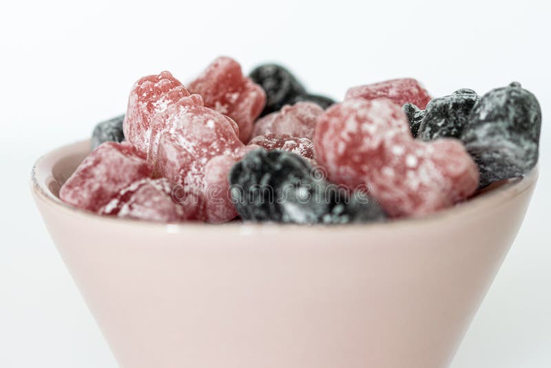 Eine Gruppe rosafarbener und schwarzgeliger Süßigkeiten in einer rosa Schüssel stockbild Eine Gruppe rosafarbener und schwarzgeliger Süßigkeiten in einer rosa Schüssel stockbild
