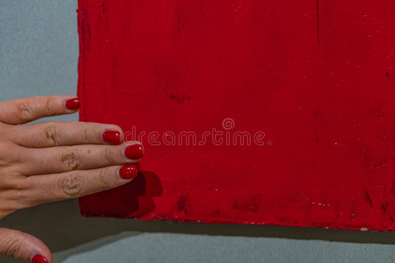 Eine Hand berührt ein lebendiges abstraktes rotes Bild vor einem weißen Hintergrund in diesem Bild und betont persönliche Interakt stockfotografie