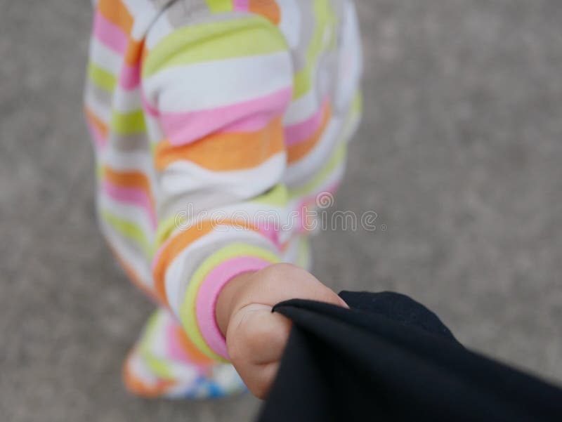 Eine Hand eines kleinen Babys, das ihre Vatihosen zieht lizenzfreie stockbilder Eine Hand eines kleinen Babys, das ihre Vatihosen zieht lizenzfreie stockbilder