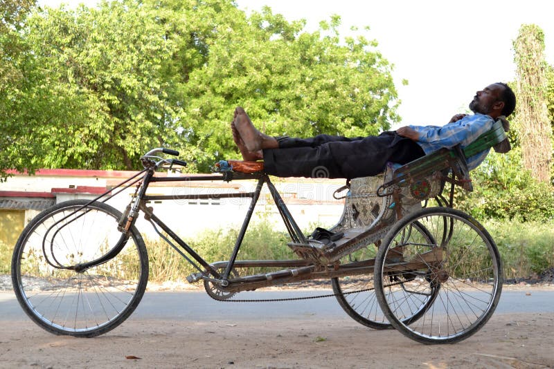 Eine indische Rikschaabziehvorrichtung, die in der merkwürdigen Position stillsteht stockfotos Eine indische Rikschaabziehvorrichtung, die in der merkwürdigen Position stillsteht stockfotos