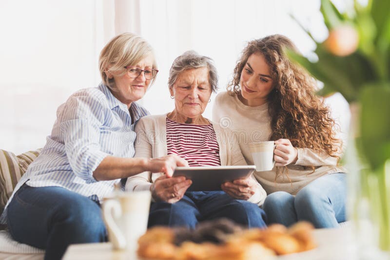 Eine Jugendliche, eine Mutter und eine Großmutter mit Tablette zu Hause stockfotos