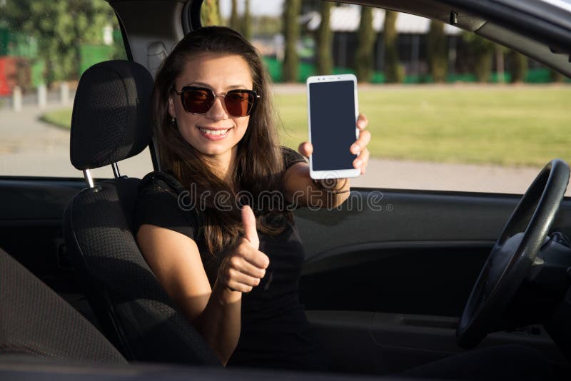 Eine junge Frau im carh Griff ein intelligentes Telefon mit den Daumen oben stockfotografie Eine junge Frau im carh Griff ein intelligentes Telefon mit den Daumen oben stockfotografie