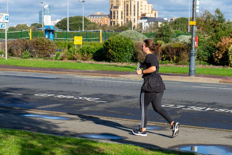 Eine junge Frau joggt oder läuft alleine am Straßenrand stockbilder Eine junge Frau joggt oder läuft alleine am Straßenrand stockbilder