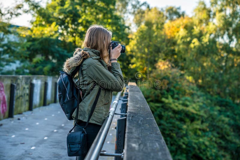 Eine junge Frau steht auf einer Brücke und macht ein Foto lizenzfreie stockfotografie Eine junge Frau steht auf einer Brücke und macht ein Foto lizenzfreie stockfotografie
