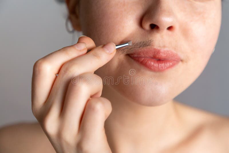 Eine junge Frau zupft ihr Haar über ihrer oberen Lippe mit Pinzette Das Konzept des Loswerdens des unerwünschten Gesichtshaares stockfotos Eine junge Frau zupft ihr Haar über ihrer oberen Lippe mit Pinzette Das Konzept des Loswerdens des unerwünschten Gesichtshaares stockfotos