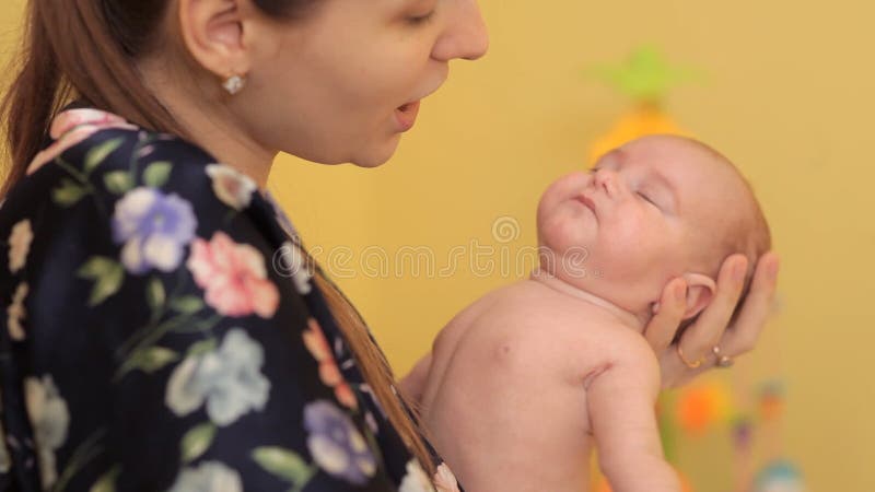 Eine junge Mutter schaukelt auf die Arme ihres Babys Kinderausdehnungen beim Schaukeln für Schlaf