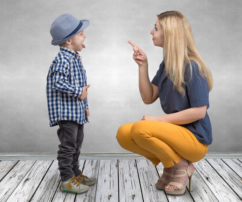 Eine junge Mutter schilt ihren frechen kleinen Sohn Jungenvertretungszunge und Plagegeistmutter stockbild Eine junge Mutter schilt ihren frechen kleinen Sohn Jungenvertretungszunge und Plagegeistmutter stockbild