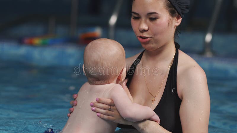 Eine junge Mutter unterrichtet das schwimmen seines jungen Sohns im Pool