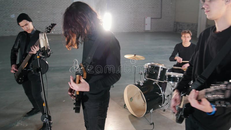 Eine junge Rockgruppe, die eine Wiederholung in einer Garage hat Mitglieder einer Gruppe, die schwarze Kleidung trägt lizenzfreies stockfoto Eine junge Rockgruppe, die eine Wiederholung in einer Garage hat Mitglieder einer Gruppe, die schwarze Kleidung trägt lizenzfreies stockfoto