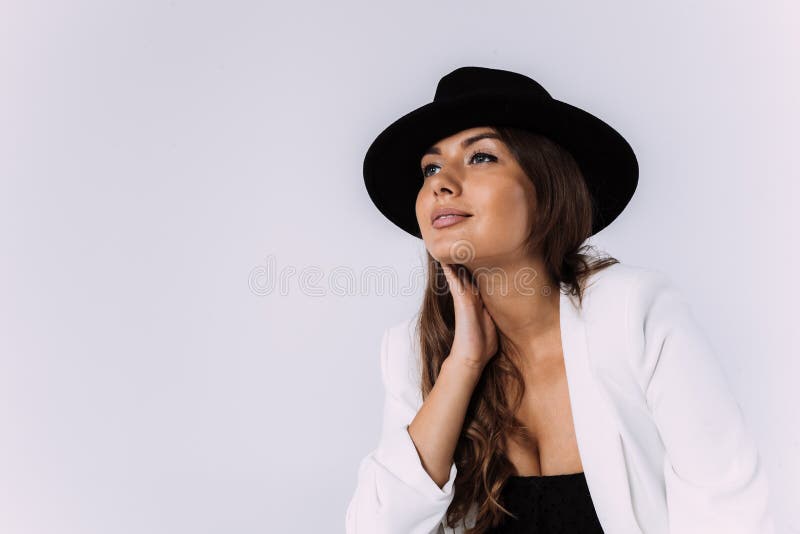 Eine lachende und Lächeln kastanienbraune behaarte Frau in einem weißen Kleid und in einem schwarzen Hut.. sittion auf der hölzern stockfoto