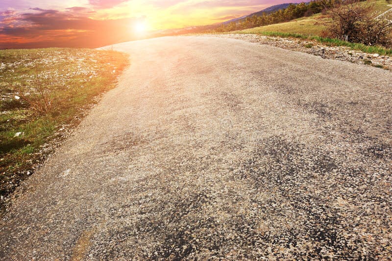 Eine leere Landstraße gegen einen Nachthimmel mit Sonnenuntergang lizenzfreie stockbilder