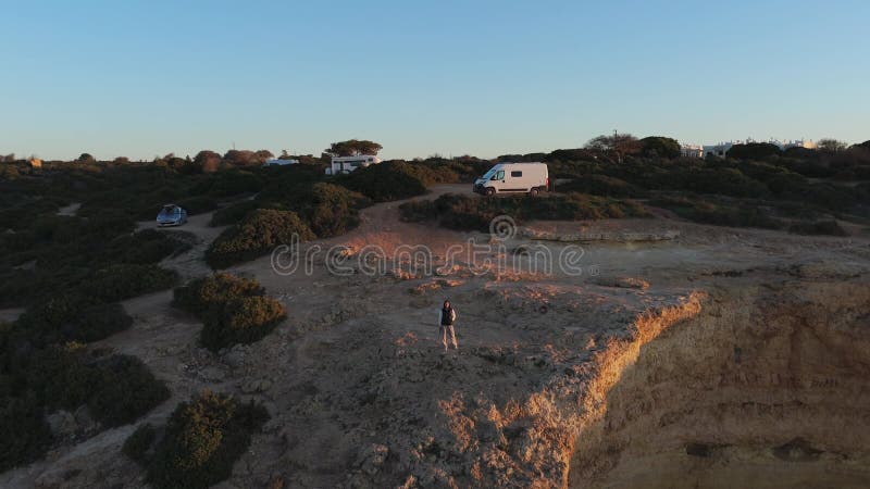 Eine malerische Klippe mit Wohnwagen und einem einsamen Reisenden, der den Sonnenuntergang der Algarve genießt. Highlights Natur u stock video