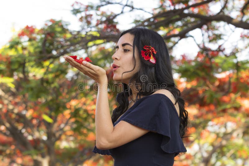 Eine mexikanische junge Dame, die Blätter von Tabachin Tree bläst lizenzfreie stockfotos Eine mexikanische junge Dame, die Blätter von Tabachin Tree bläst lizenzfreie stockfotos