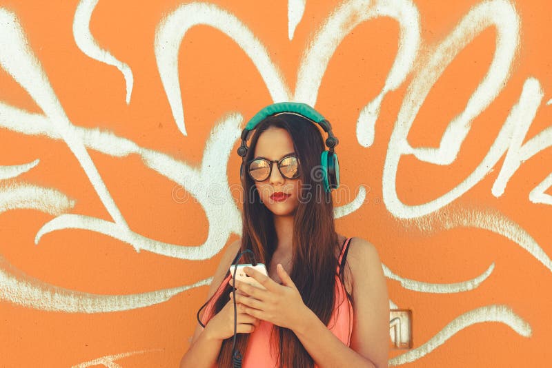 Eine moderne junge Dame unter Verwendung ihres Handys, zu hören Musik mit ihren Kopfhörern stockfoto Eine moderne junge Dame unter Verwendung ihres Handys, zu hören Musik mit ihren Kopfhörern stockfoto