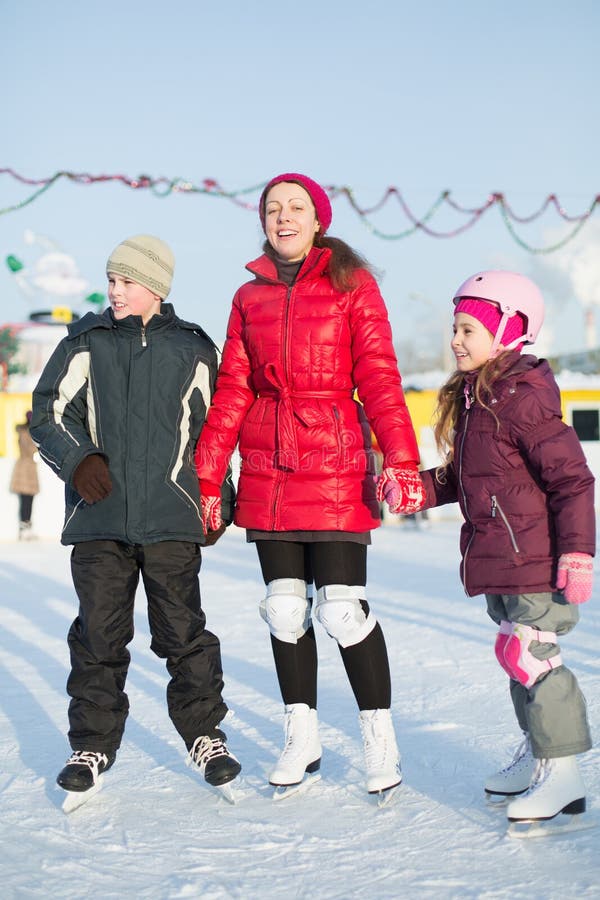 Eine Mutter mit den Kindern, die auf der Eisbahn im Freien stehen lizenzfreies stockbild Eine Mutter mit den Kindern, die auf der Eisbahn im Freien stehen lizenzfreies stockbild