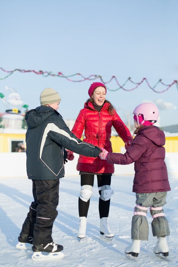 Eine Mutter mit Kindern laufen auf Eisbahn im Freien eis lizenzfreie stockfotos Eine Mutter mit Kindern laufen auf Eisbahn im Freien eis lizenzfreie stockfotos
