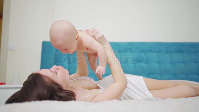 Eine Mutter spielt mit dem Baby auf dem Bett. Gesundheit von Müttern und Kindern.