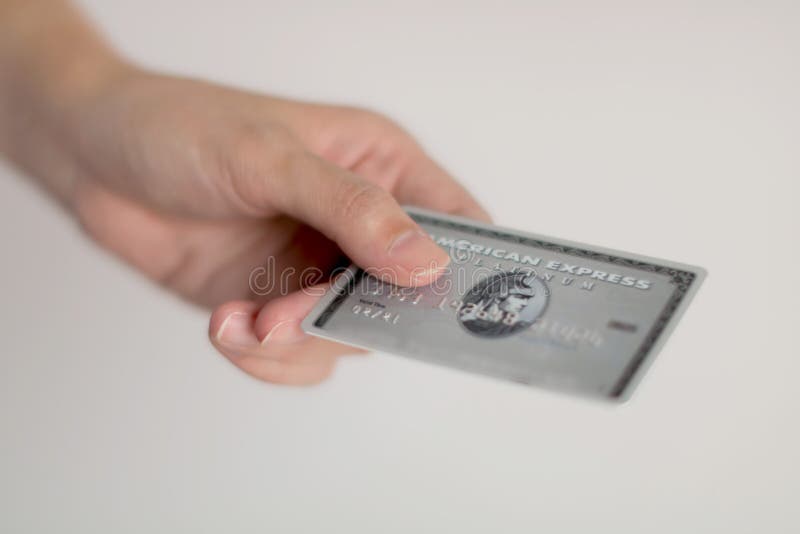 BANGKOK, THAILAND - April 1, 2018: A hand outreaching an American express credit card; one of most popular credit cards worldwide; for payment on white background with selected focus. BANGKOK, THAILAND - April 1, 2018: A hand outreaching an American express credit card; one of most popular credit cards worldwide; for payment on white background with selected focus