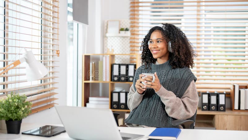 Eine positive verträumte schwarze Frau träumt davon, beim Blick nach draußen und Kaffee zu trinken lizenzfreies stockbild