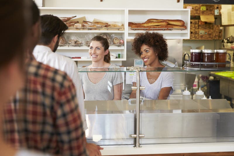 Eine Reihe von Kunden diente durch zwei Frauen an einem Imbiss lizenzfreies stockfoto Eine Reihe von Kunden diente durch zwei Frauen an einem Imbiss lizenzfreies stockfoto
