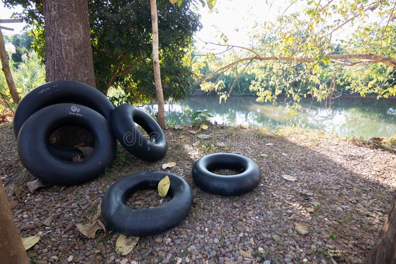 Eine ruhige Aussicht über den Fluss mit verlassenen schwarzen Reifen inmitten der Natur. perfekt für anspruchsvolle oder naturverb lizenzfreies stockbild