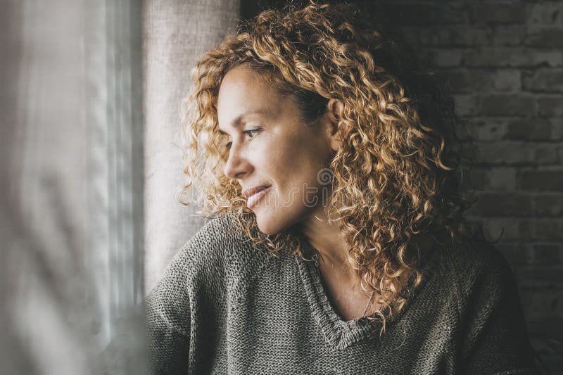 Eine ruhige erwachsene Frau, die nach Hause schaut, mit friedlichem Gesichtsausdruck und wenig Lächeln. selbstbewusste Frau lizenzfreies stockfoto