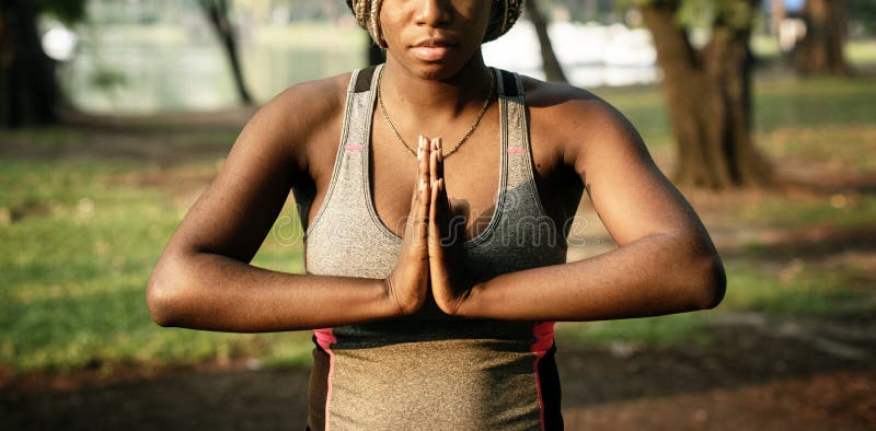 Eine schwarze Frau, die Yoga in einem Park tut lizenzfreies stockfoto Eine schwarze Frau, die Yoga in einem Park tut lizenzfreies stockfoto