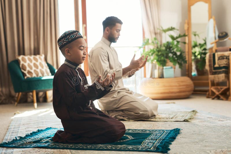 Eine schöne Religion der Brüderlichkeit und Hingabe. ein junger Muschelmensch und sein Sohn beten zu Hause im Salon. stockfoto