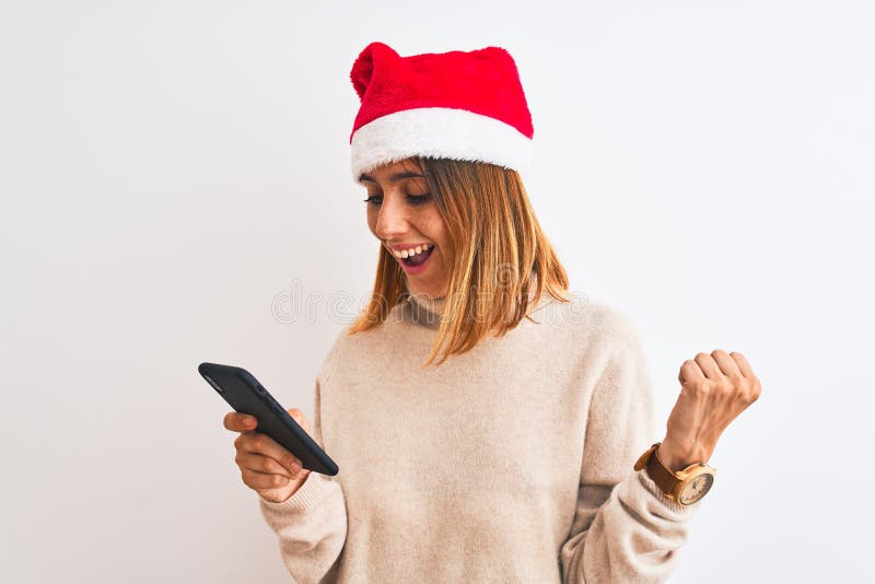 Eine schöne Rothoutiquin, die Weihnachtsmütze trägt und mit dem Smartphone schreit stolz und feiert Sieg und Erfolg sehr lizenzfreie stockfotografie
