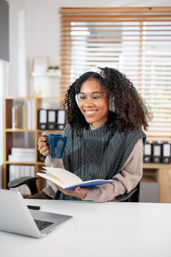 Eine schöne schwarze Frau mit lockigen Haaren arbeitet von zu Hause aus oder lernt online lizenzfreies stockbild