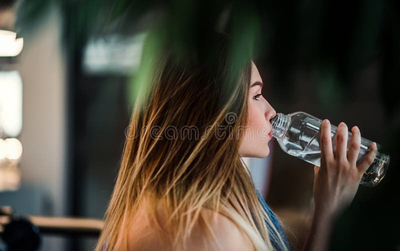 Eine Seitenansicht der Stellung des jungen Mädchens oder der Frau in einer Turnhalle, Trinkwasser lizenzfreies stockbild Eine Seitenansicht der Stellung des jungen Mädchens oder der Frau in einer Turnhalle, Trinkwasser lizenzfreies stockbild