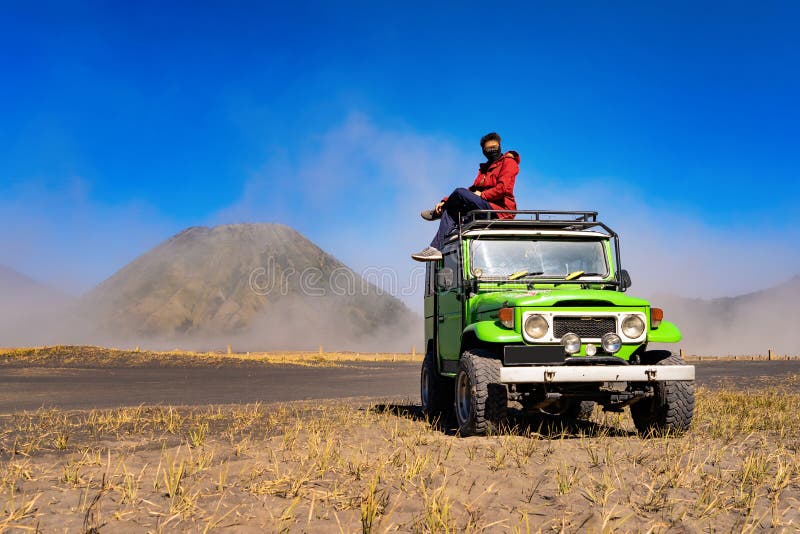 Eine tragende Maske des asiatischen Mannes und Sitzen auf Jeepauto am Berg Bromo Ein aktiver Vulkan, eine der besuchten Touristen lizenzfreie stockfotos Eine tragende Maske des asiatischen Mannes und Sitzen auf Jeepauto am Berg Bromo Ein aktiver Vulkan, eine der besuchten Touristen lizenzfreie stockfotos