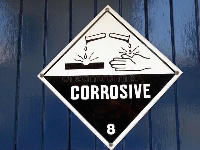 A sign warning care to be taken because the area has corrosive chemicals present in an industrial work area. A sign warning care to be taken because the area has corrosive chemicals present in an industrial work area