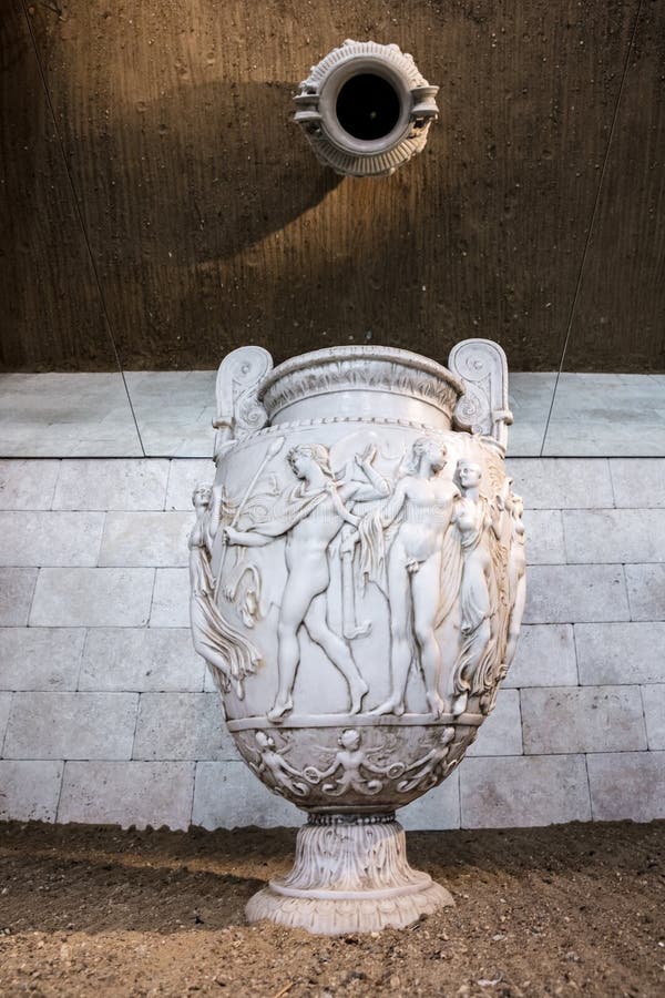 Eine weiße Vase mit einer Frau darauf sitzt auf einem Steinboden stockfoto